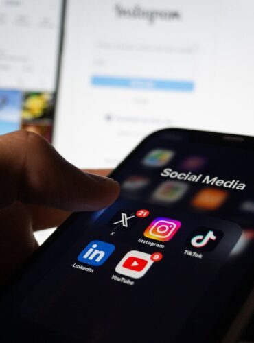 A person holding a smart phone with social media on the screen